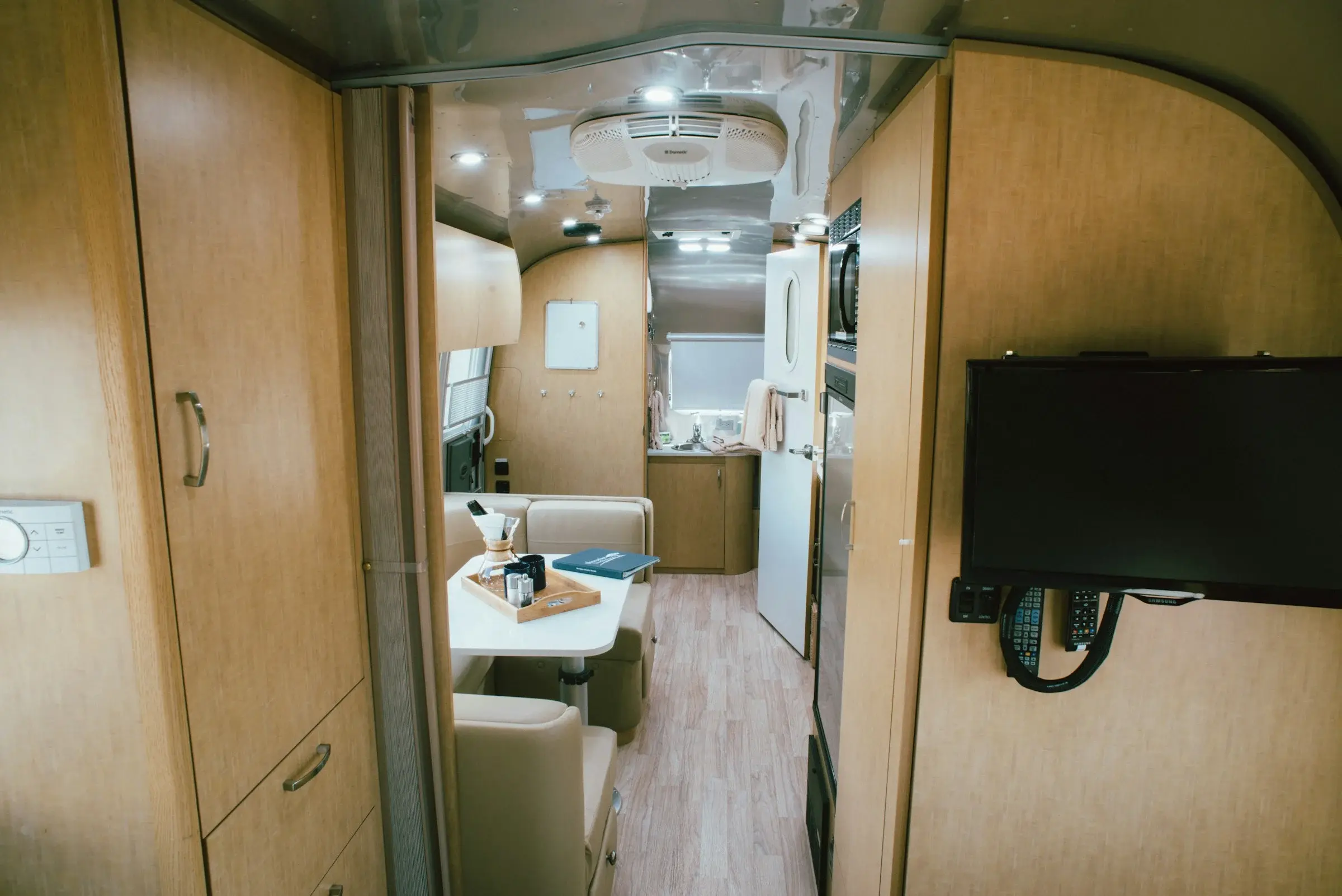 Interior of a larger RV with hallway cabinets and a mounted television