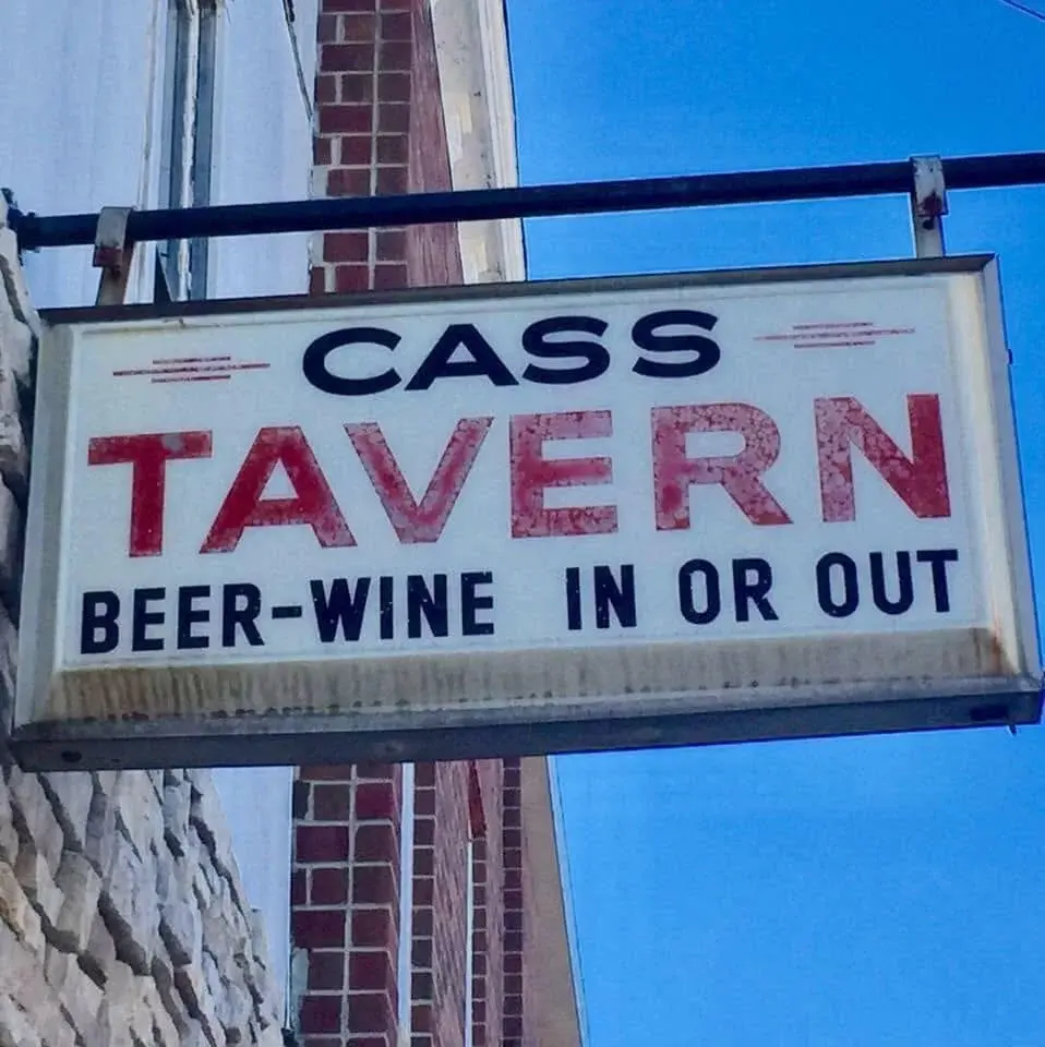 Sign reading "Cass Tavern, Beer-Wine In or Out" against a blue sky.