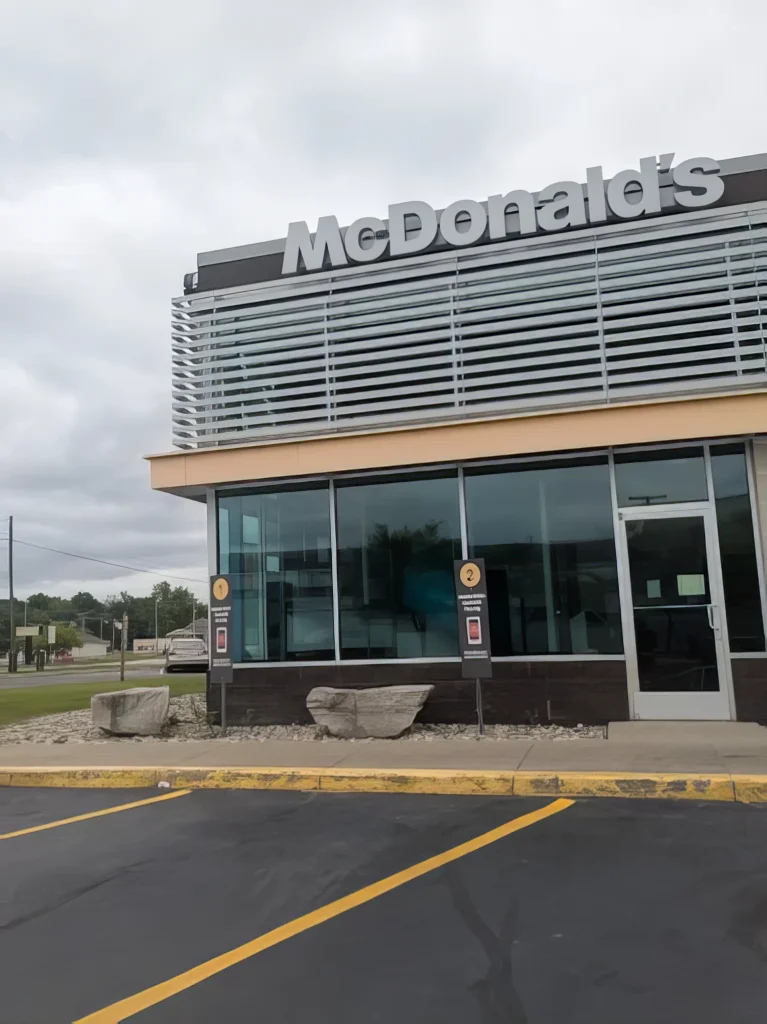 Exterior of a McDonald's restaurant with a modern design, featuring large windows and a parking area in front.