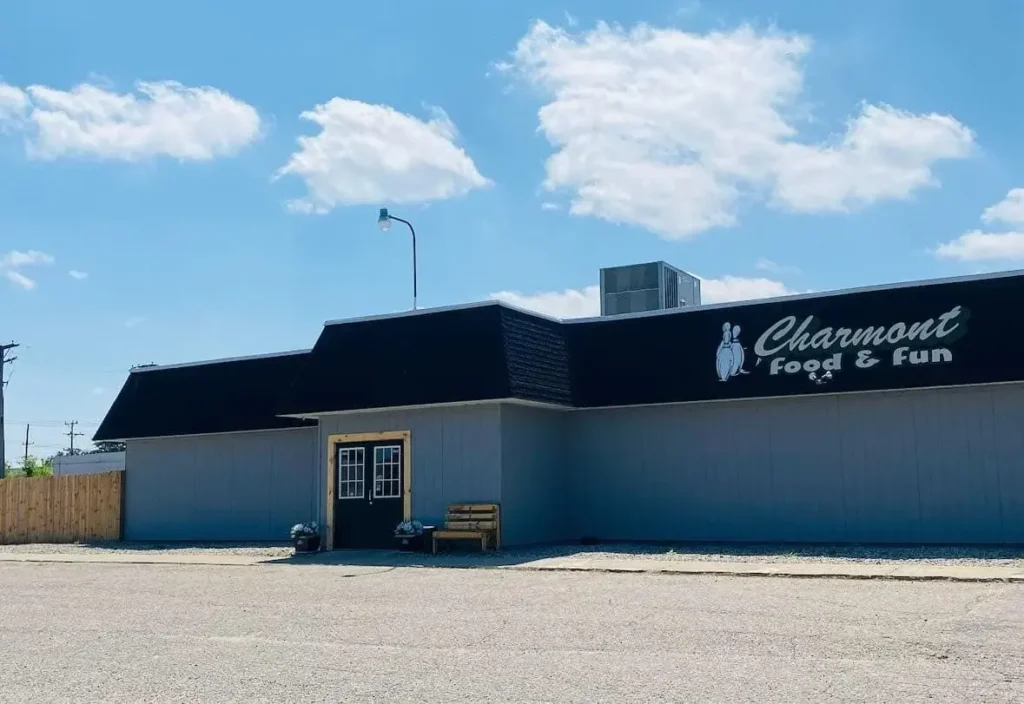 Exterior of Charmont Food & Fun, a building with a dark roof and light gray walls, under a blue sky with clouds.