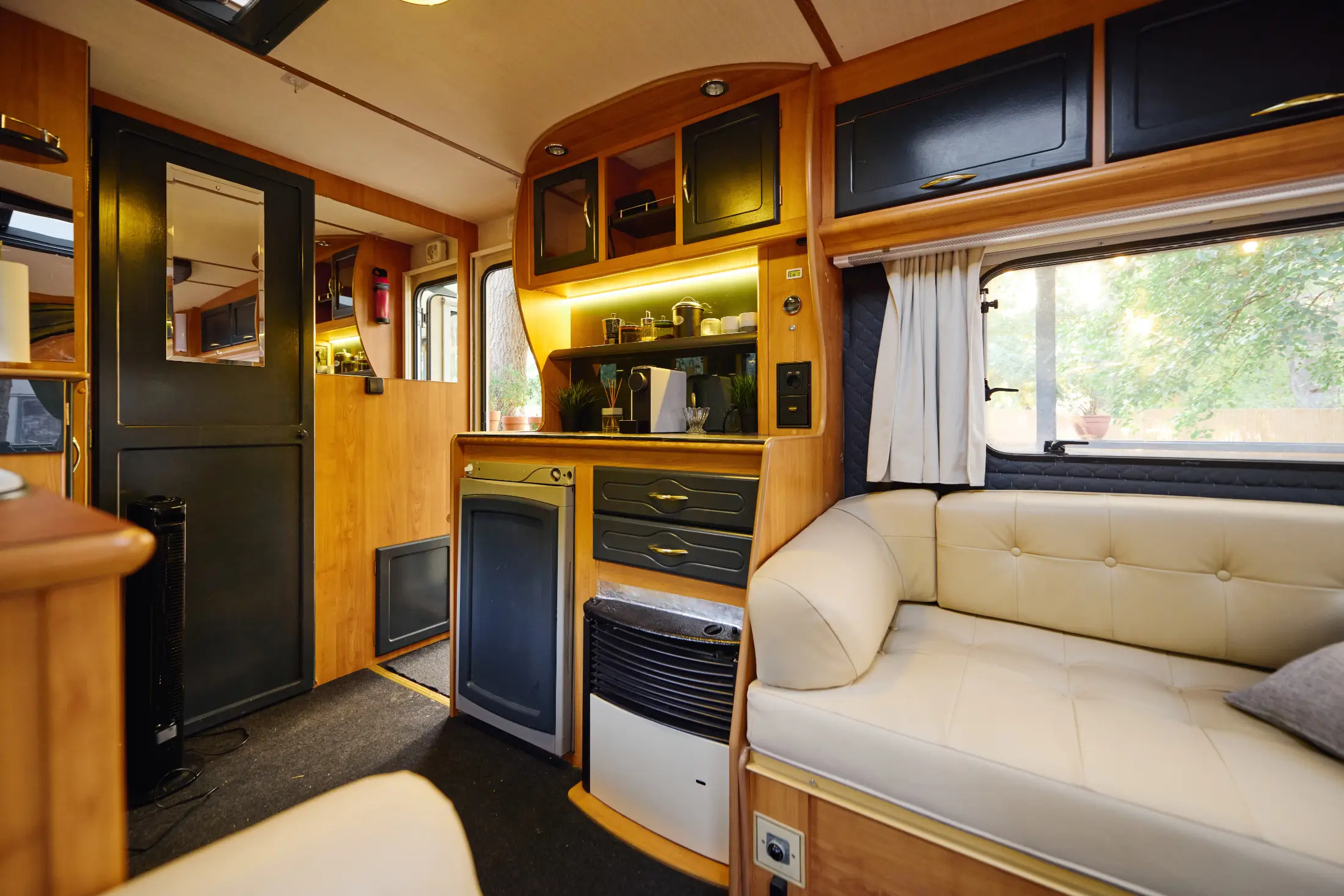 Interior of a small travel trailer with kitchen cabinets, seating, and appliances