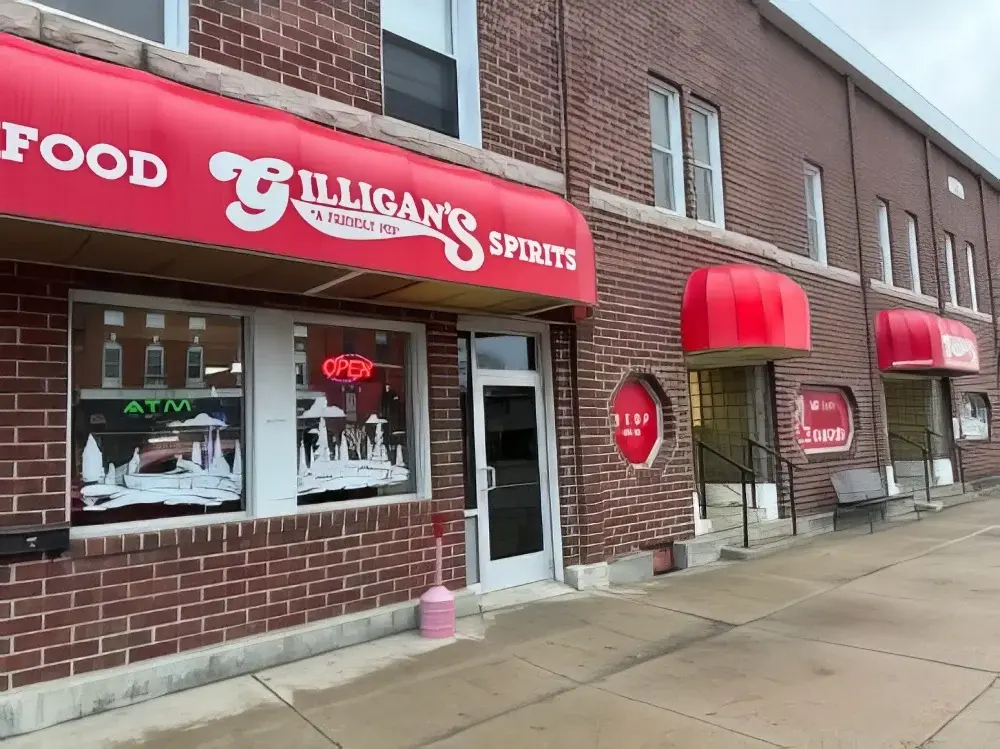 Brick building with red awnings labeled "Gilligan's Spirits" and "Food." A neon "Open" sign is visible in the window.