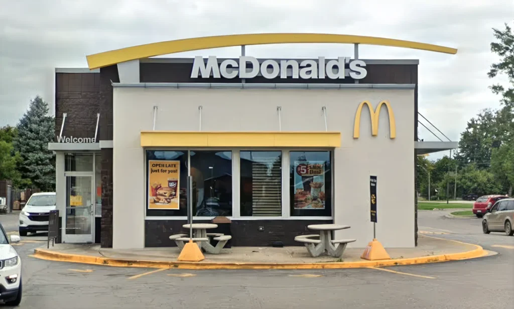 Exterior of a McDonald's restaurant with outdoor seating and promotional posters on the windows.
