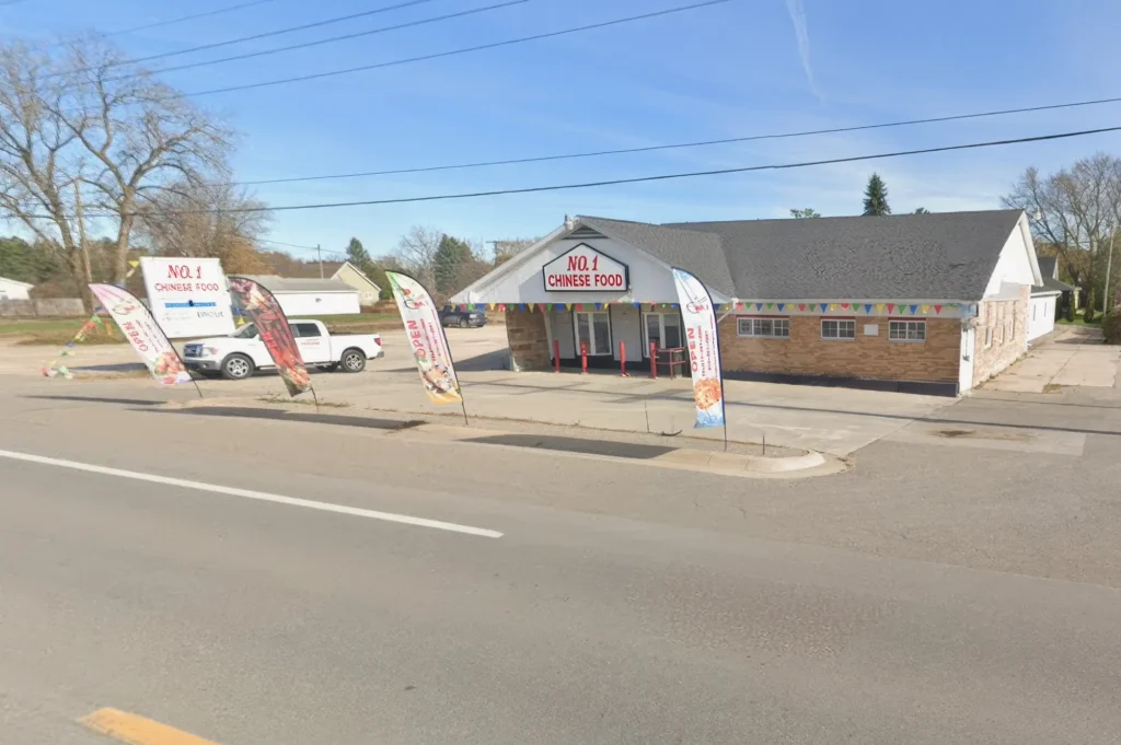 Exterior of a restaurant named "No. 1 Chinese Food" with colorful flags and a parked truck.