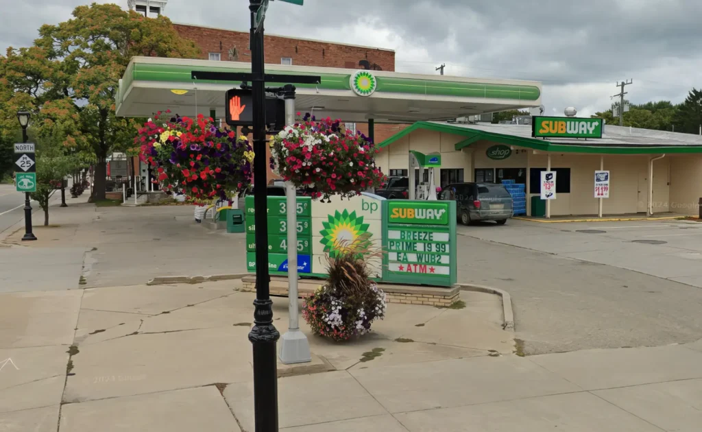 BP gas station with a Subway, flower baskets, and a pedestrian signal on a cloudy day.