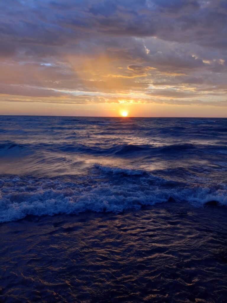 Sunset over Lake Huron with waves and a cloudy sky at Lexington Park.